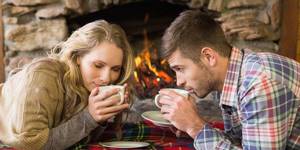 Парень и девушка пьют чай возле камина