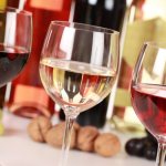 Три бокала вина на фоне бутылок